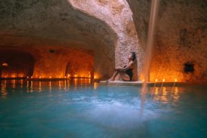 una donna seduta sul bordo di una piscina d'acqua di Hotel Zentik Project & Saline Cave a Valladolid