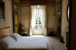 a bedroom with a bed and a large window at Antica Dimora Gallo Basteris in Piozzo