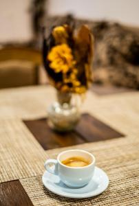 a cup of coffee on a table with a vase of flowers at Alex apartment in Velingrad