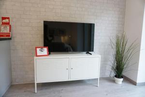 a white entertainment center with a tv on a brick wall at AL d' Cacilhas Studio in Almada
