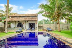 une villa avec une piscine et des palmiers dans l'établissement Villananda, à Ambalangoda