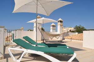 a green and white chair and umbrella on a roof at Alto da Ria 37 in Alvor