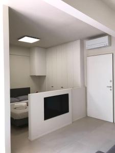 a white living room with a tv and a bed at Olivo House 1 in Portovenere