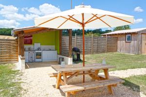 einen Picknicktisch mit Sonnenschirm im Hinterhof in der Unterkunft Les Yourtes d'Agnac in Agnac