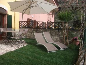 - deux chaises et un parasol sur l'herbe dans l'établissement APPARTAMENTO AURORA Val di Sogno, à Malcesine