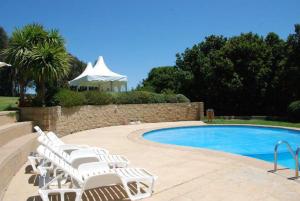 a group of white lounge chairs next to a swimming pool at Departamentos Mednav Mantagua in Concón