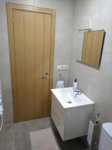 a bathroom with a white sink and a wooden door at Casa rural El Gato Negro in Trefacio +31 photos