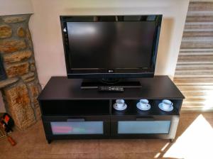 a flat screen tv sitting on top of a black entertainment center at Casa rural El Gato Negro in Trefacio
