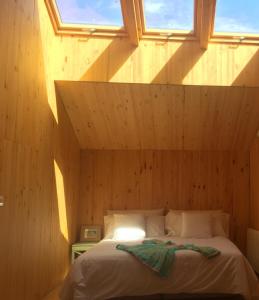 a bed in a wooden room with two windows at La Holandesa in Cercedilla