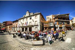 a group of people sitting at tables on a city street at La Holandesa in Cercedilla