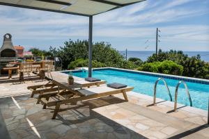 a swimming pool with a picnic table and an umbrella at Villa Sea front in Skala