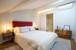um quarto com uma grande cama branca e uma cabeceira vermelha em Lofts - Casa do Metro na Póvoa do Varzim