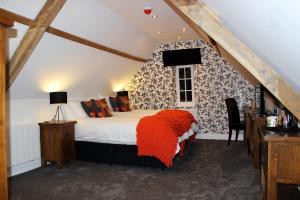 Kings Head Hotel في North Elmham: غرفة نوم مع سرير مع بطانية برتقالية عليه