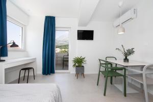 a white bedroom with a table and chairs and a window at Apartments No 18 in Tučepi
