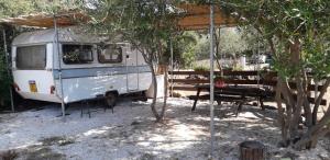 una furgoneta estacionada bajo una tienda con una mesa de picnic en Su Pinnetu, en Orosei