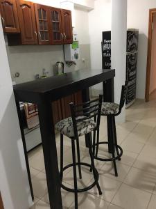 a kitchen with a black counter and two chairs at Alonso 540 Departamento in Río Cuarto