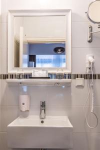 ein weißes Badezimmer mit einem Waschbecken und einem Spiegel in der Unterkunft Hotel Amstelzicht in Amsterdam