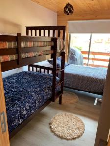 1 dormitorio con 2 literas y alfombra en Casa con acceso directo a playa en condominio en Pichilemu