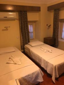 2 Betten in einem Hotelzimmer mit weißer Bettwäsche in der Unterkunft Antik Ridvan Hotel in Cesme