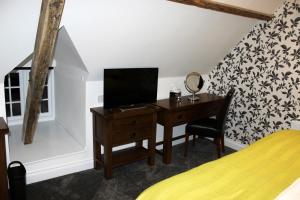 1 dormitorio con escritorio, TV y cama en Kings Head Hotel en North Elmham