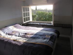 a bedroom with a bed and a window with a blanket at Le Gite de Fanny in Saintes-Maries-de-la-Mer