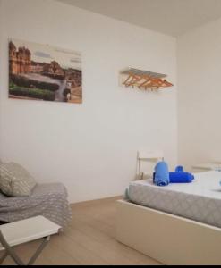 ein Schlafzimmer mit einem Bett, einem Stuhl und einem Gemälde in der Unterkunft Casa Andolina White in Noto