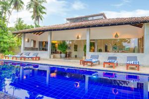 a villa with a swimming pool and a house at Gangananda in Ambalangoda