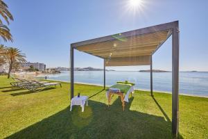a pavilion with two chairs and a table on the grass by the ocean at Hotel Torre del Mar - Ibiza in Playa d'en Bossa