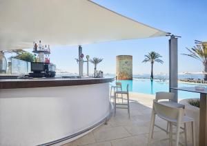 a bar with chairs and a view of a pool at Hotel Torre del Mar - Ibiza in Playa d'en Bossa