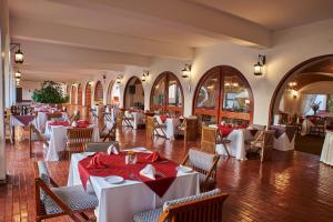 un restaurante con mesas blancas y sillas con servilletas rojas en DM Hoteles Nasca, en Nazca