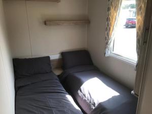 a small room with two beds and a window at 3 bedroom deluxe caravan in Longniddry