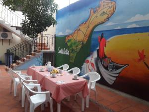 una mesa y sillas frente a una pared con un mural en Hostal Santa Cecilia, en Ríohacha