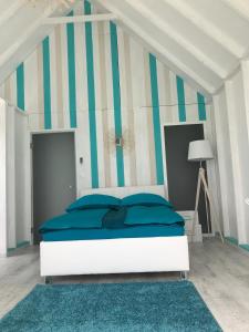 a bedroom with a bed with blue pillows and striped wall at LupaGlamping in Budakalász