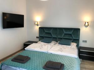 sypialnia z łóżkiem z zielonym zagłówkiem i telewizorem z płaskim ekranem w obiekcie Apartament LUX Green basen SPA Pięć Mórz Sianożęty w Sianożętach