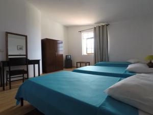 a bedroom with two beds and a desk and a mirror at Bed and breakfast Residencial Maravilha in Mindelo