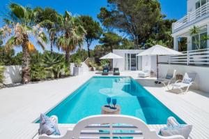 a swimming pool with chairs and a house at Can Love in Cala Comte