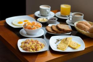 a wooden table with plates of breakfast food on it at Hotel Ottavis in Chiclayo