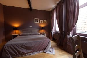 a bedroom with a bed and two windows at Hotel Boterhuis in Bruges