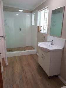 a white bathroom with a sink and a shower at Emfuleni Place by the River in Champagne Valley