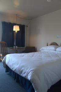 a bedroom with a large white bed and a table at Fortress Inn Louisbourg in Louisbourg +24 photos