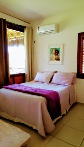 Bangalô Eco Residence Flecheiras في فليشيراز: غرفة نوم مع سرير مع ملاءات أرجوانية ونافذة