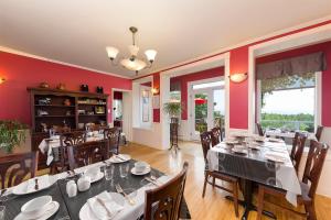 uma sala de jantar com mesas e cadeiras e paredes vermelhas em Auberge Fleurs de Lune em La Malbaie