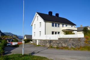 een wit huis met een zwart dak op een straat bij The Manor House in Hamnøy in Reine