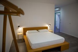 a bedroom with a bed with white sheets and two tables at La Casetta - Rooms & Garden in San Ferdinando