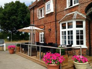 a patio with a table and an umbrella and flowers at Kings Head Hotel in North Elmham