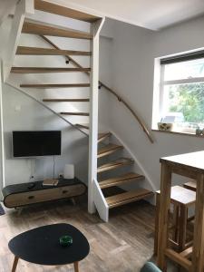 a living room with a staircase and a tv at Studio Het Kommertjeshof in Burgh Haamstede