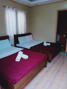 duas camas num quarto com lençóis roxos em East Square Inn em Bacolod