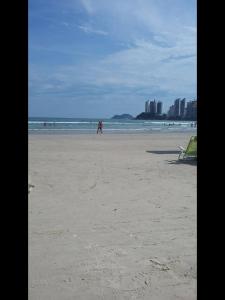 una playa con gente en el agua y una persona caminando en Apartamento Vista Mar - 2 Garagens, en Guarujá