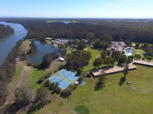 een luchtzicht op een huis met een tennisbaan en een meer bij Tuncurry Lakes Resort in Tuncurry