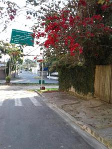 un panneau de rue à côté d'une brousse avec des fleurs rouges dans l'établissement Kitconforto, à Guarujá
